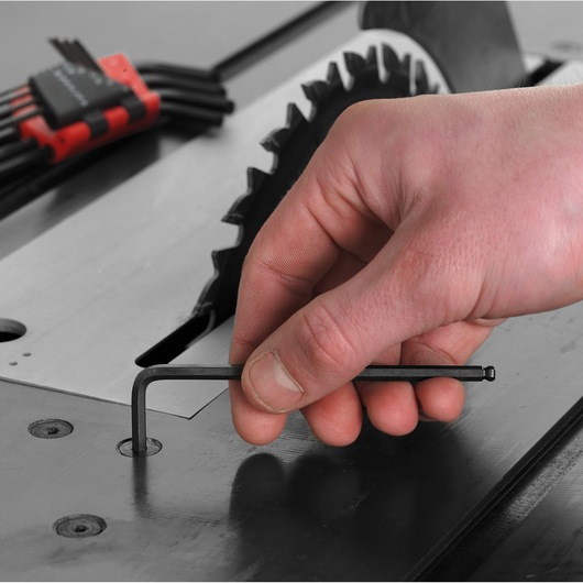 Facom 83SH.3/16 hex key photography, hand using black hex key near saw blade on workbench.