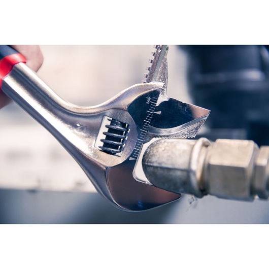 Facom adjustable wrench 101_10GR clamping metal pipe, close-up photography.