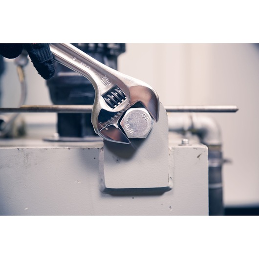 Facom adjustable wrench 101.18PB tightening a large hex bolt in an industrial setting, close-up photography.