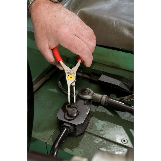 Facom 167A9 red-handled snap ring pliers used on mechanical parts, close-up photography.