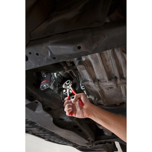 Facom 170A_25 adjustable pliers with red handles used on a car undercarriage, close-up action.
