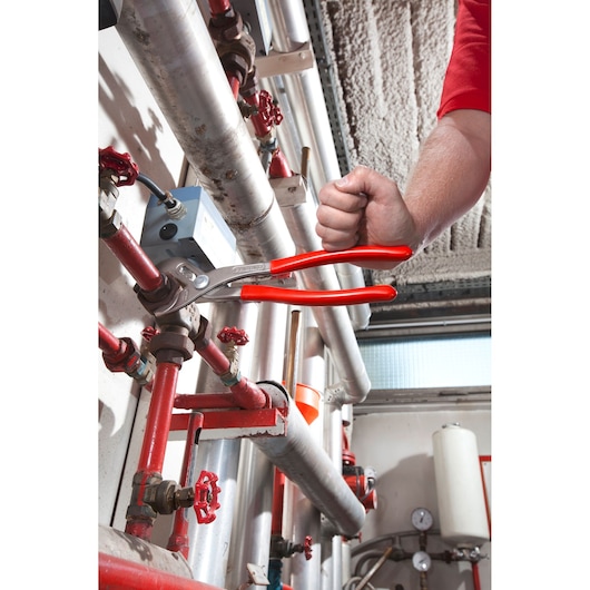 Facom 170A_30 pliers with red handles being used on industrial pipes in a workshop setting.