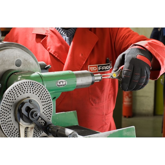 Facom 177A18 pliers held by gloved hand next to green industrial machine in workshop setting.