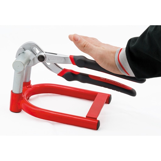 Facom 181A_25CPE adjustable pliers with red and black handles shown in use on a metal pipe, side angle.