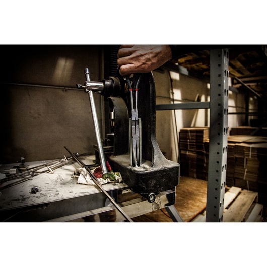 Facom 185_34L hand tool in use in a workshop setting with a vice and metal rods on a workbench.