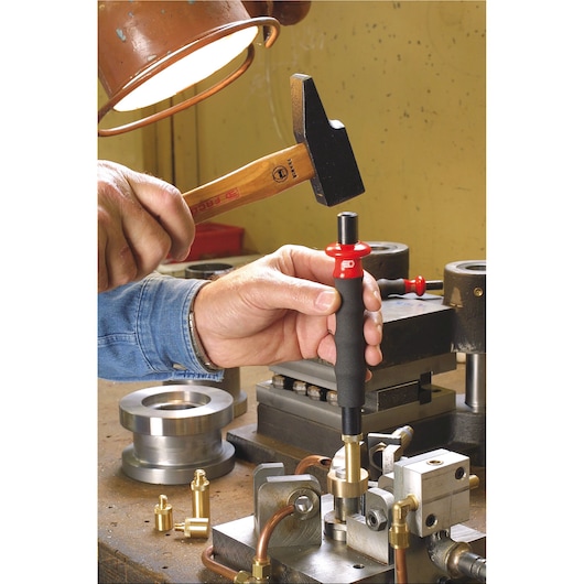 Facom 200H_50 hand tool used with a hammer on a metalworking bench, showing precision mechanical work.