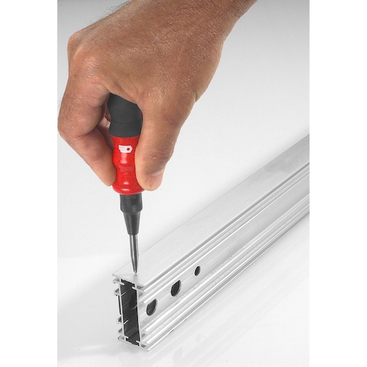 Photo of Facom 257.GPB automatic center punch with red and black handle in use on a metal profile.