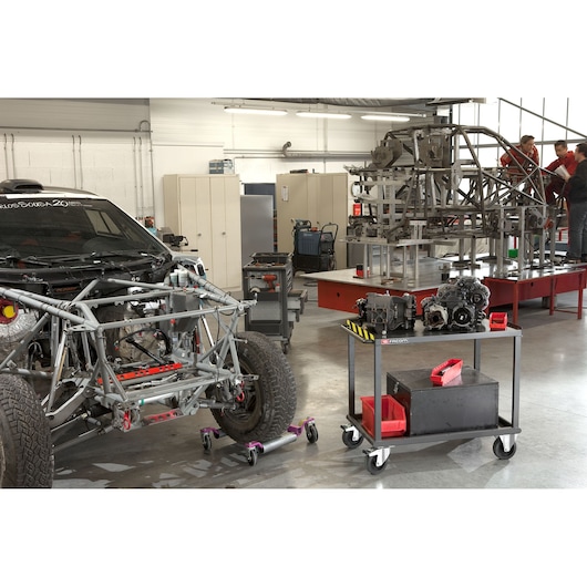 Facom 2702 photography of workshop with car frame, tool cart, and engine parts, wide angle view.