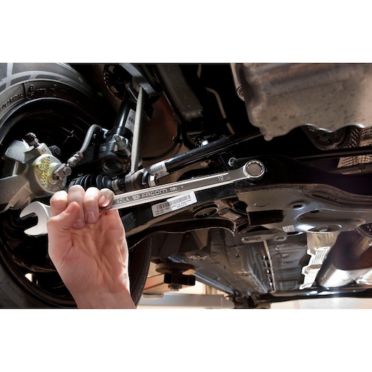 Photo of a Facom 40_30LA combination wrench being used to tighten a bolt on a car suspension undercarriage.