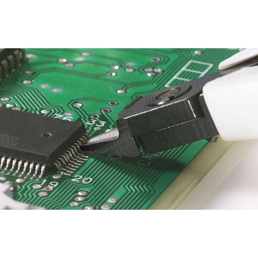 Facom 417_SPMT precision cutter trimming electronic component leads on green circuit board, close-up.