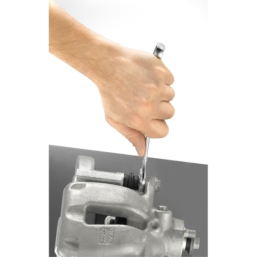Photo of hand using Facom 440_12 combination spanner on a metal automotive part, close-up angle.