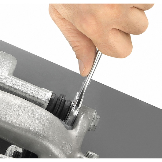 Facom 440_14 wrench in use tightening a bolt on metal machinery, close-up, hand visible.