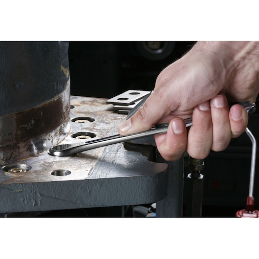 Facom 440.9/16 combination wrench in use tightening a bolt on metal machinery, close-up photography.