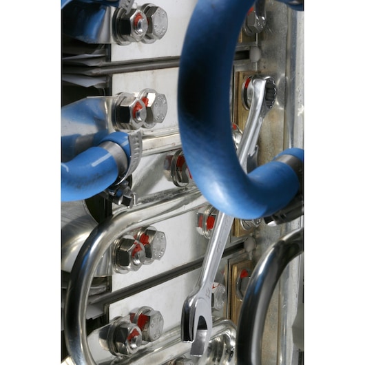 Facom 440.9/16 open-end wrench in use on metal bolts with blue hoses in industrial setting.