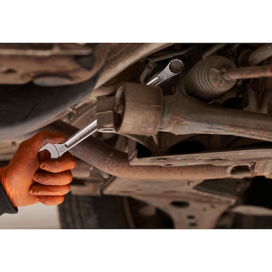 Facom 440XL_19 combination wrench in use on vehicle suspension, hand with orange glove holding tool.