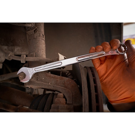 Facom 440XL_19 combination wrench used on automotive part, gloved hand holding tool, close-up.