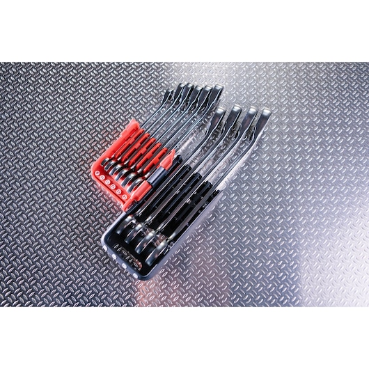 A set of Facom wrenches in two trays, one red and one black, arranged on a textured metal surface. The wrenches vary in size and are neatly organized.