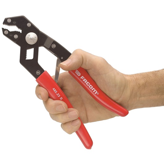 Photo of Facom 485_23 adjustable pliers with red handles, held in a right hand, white background.