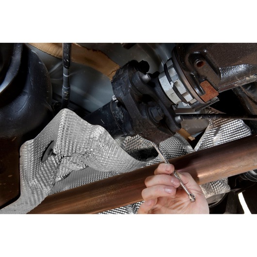 Facom 59TX_20X24 combination wrench used on car undercarriage bolt, close-up with hand holding tool.