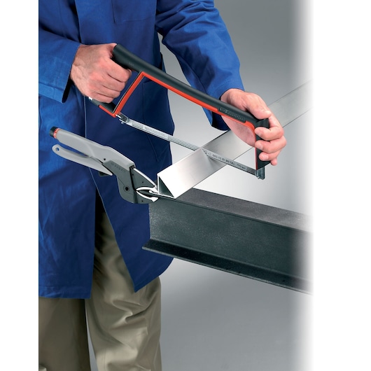 Facom 601 clamp and hacksaw cutting metal beam, close-up photography.