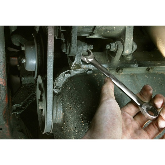 Facom 64_3_4X13_16 combination wrench used on an engine bolt, close-up of hand gripping tool.
