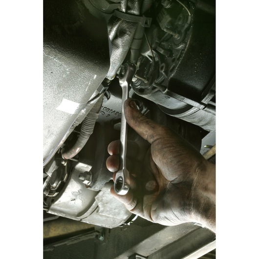 Facom 64_5_16X11_32 ratcheting combination wrench in use on car engine, close-up of mechanic hand.