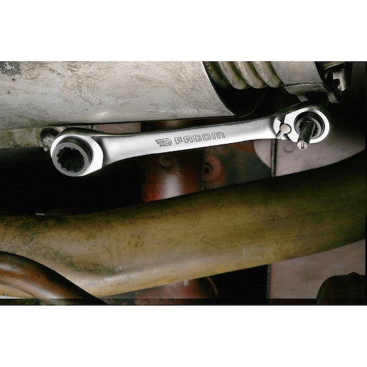Facom 64C_S2 ratcheting wrench in use on a mechanical bolt under machinery, silver finish.