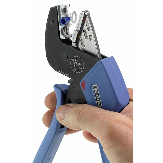 Photo of Facom hand crimping tool 673838 with blue handles in use, close-up on white background.