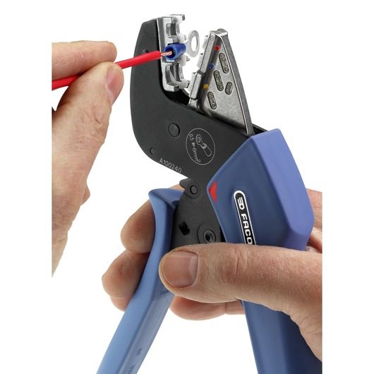 Facom 673838 crimping tool with blue handles, hand holding and crimping a red wire, close-up view.