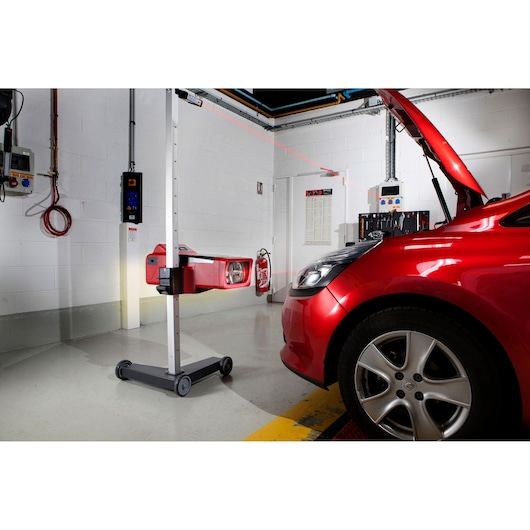 Facom 740A vehicle headlight tester with red laser guide in use on a red car, side view in workshop.