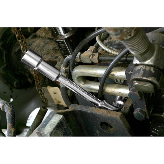 Facom 7510 socket wrench used on engine machinery, shown at work among metal pipes and bolts.