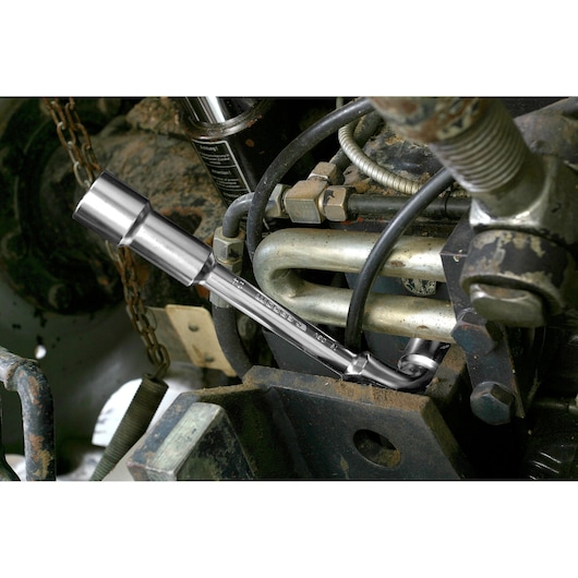 Facom 75_12 box end wrench being used to tighten a bolt on industrial machinery, close-up view.