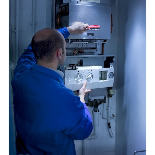 Facom 779.PENPB hand brush used by technician on boiler controls, indoor setting, side angle.