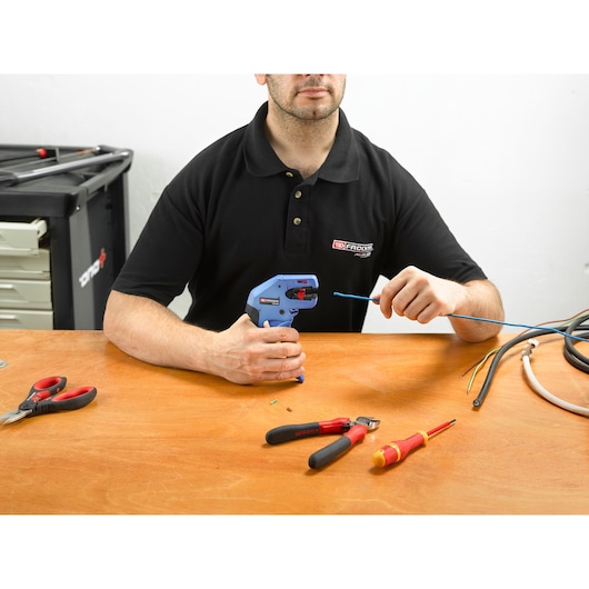 Facom 793940 wire stripping tool and hand tools on wooden workbench, technician using wire stripper.