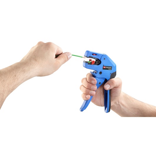 Photo of Facom 793940 automatic wire stripper tool in use, stripping green wire, close-up on white background.