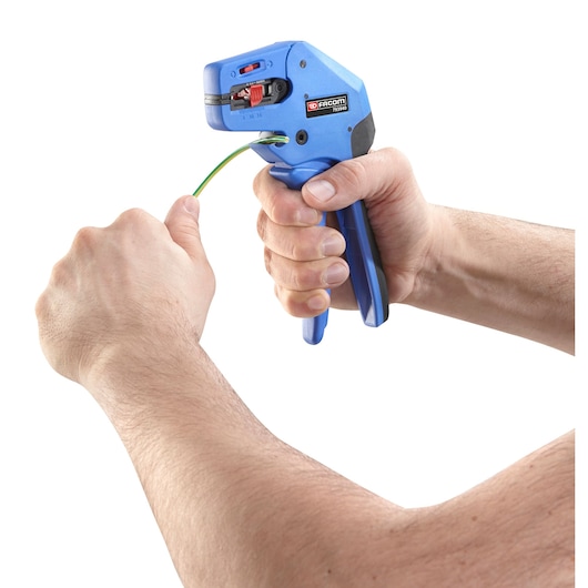 Photo of Facom 793940 automatic wire stripper tool in use on a green wire, close-up on white background.