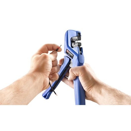 Facom wire stripper tool SKU 821416 in hand, stripping black electrical wire, white background, close-up.