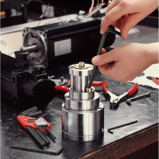 Facom 83H_24 hex key being used on a metal machine part, with additional hex keys and pliers on a workbench.