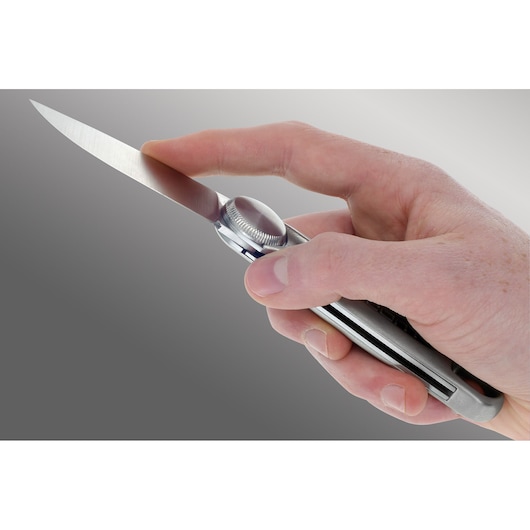Photo of Facom 840LE.PB folding utility knife held in a hand, silver handle and exposed blade, side angle.