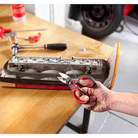 Facom 841A.3PB wire cutter with red and black handles cutting blue wire in workshop photography.