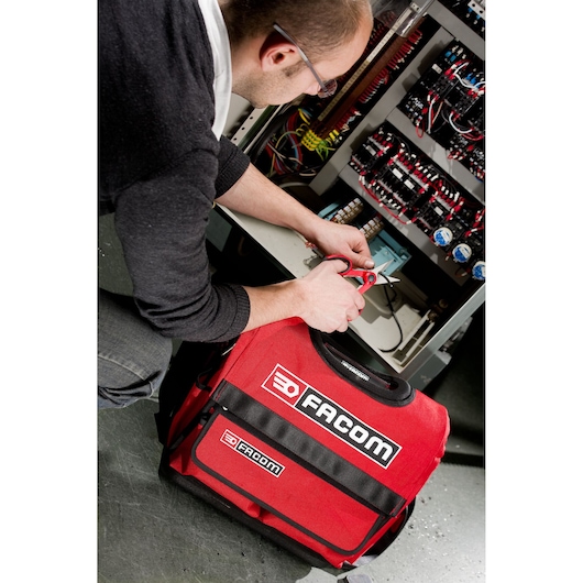 Facom 841A_4 red tool bag used by technician near electrical panel, front angle, main branding visible.