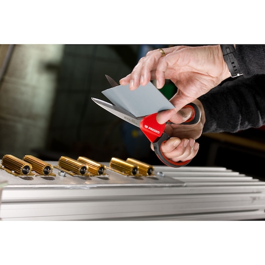 Facom 841A9 scissors cutting a grey plastic sheet, close-up view with hand holding the material.