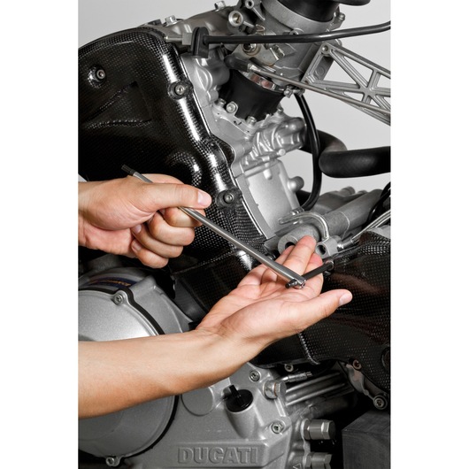 Facom 84TCD_8 hex key in use tightening bolt on motorcycle engine, close-up photo.