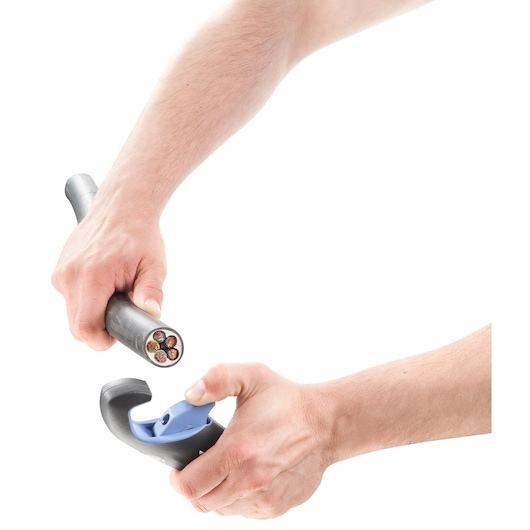 Close-up of hands using a wire stripper tool to strip insulation from a thick electrical cable, revealing multiple colored wires inside.
