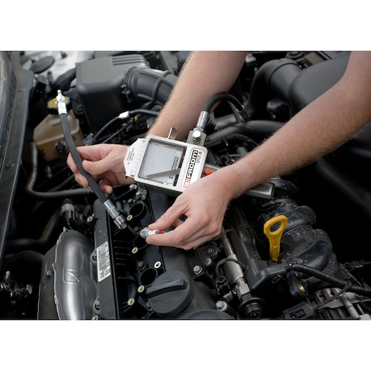 Facom 912 automotive diagnostic tool in use on a car engine, technician holding the device and cable.
