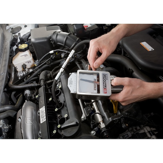 Facom 912 compression tester used on a car engine during diagnostics.
