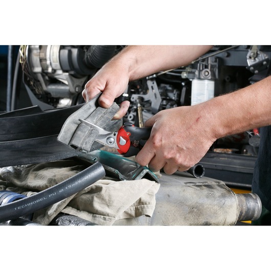 Facom 980C hand shear cutting rubber hose in workshop setting, close-up on tool and hands.