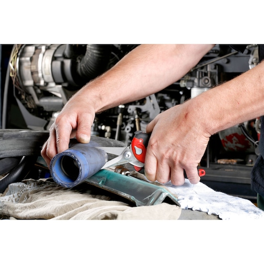 Facom 980 shears cutting a blue rubber hose in a workshop setting, close-up photo.