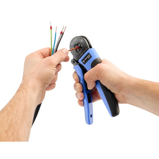 Facom 985905 wire crimping tool with blue and black handles in use on electrical wires, side angle.