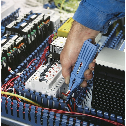Facom 985962 electrical tester used on circuit breakers in an industrial panel, close-up photo.